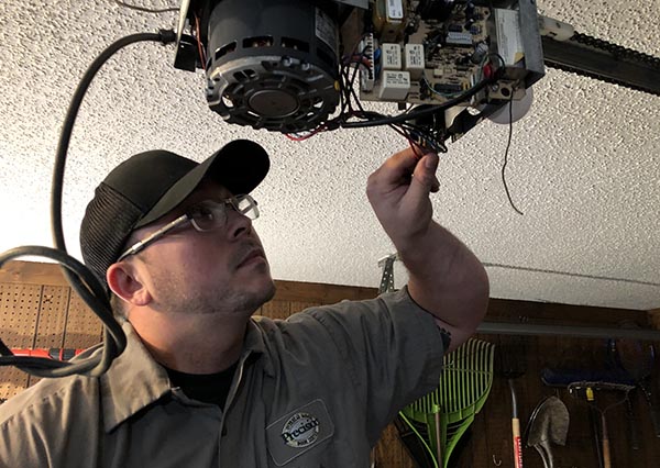 Precision Service technician looks at garage door opener