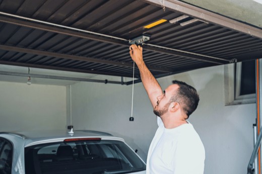 Precision Door Technician Doing Maintenance On a Noisy Garage Door